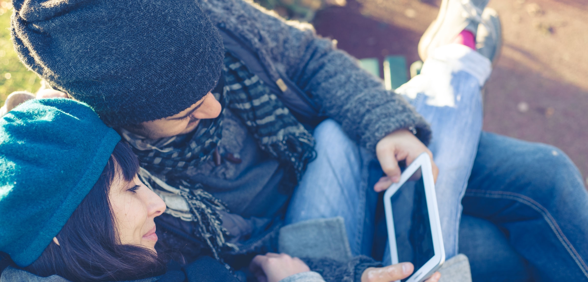 couple in love using tablet at the park in autumn