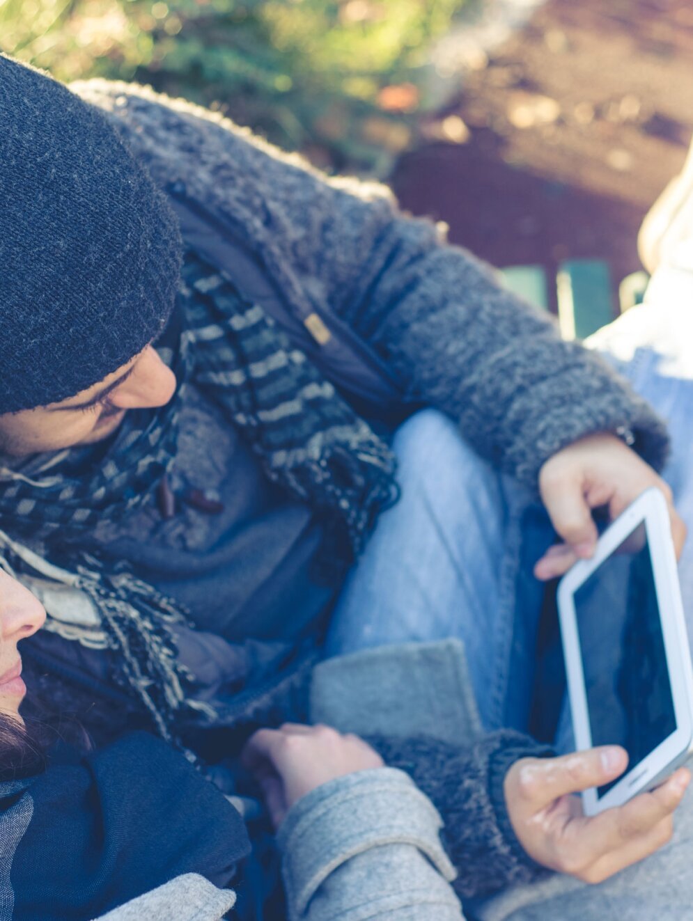 couple in love using tablet at the park in autumn