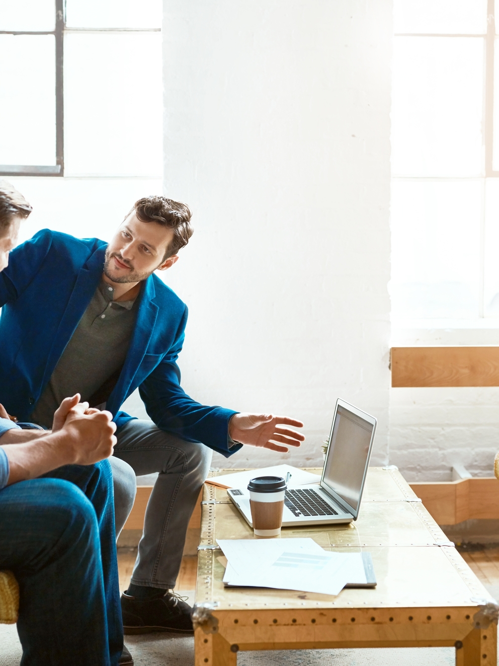Shot of two young businessmen having a discussion and using a laptop together in a modern office